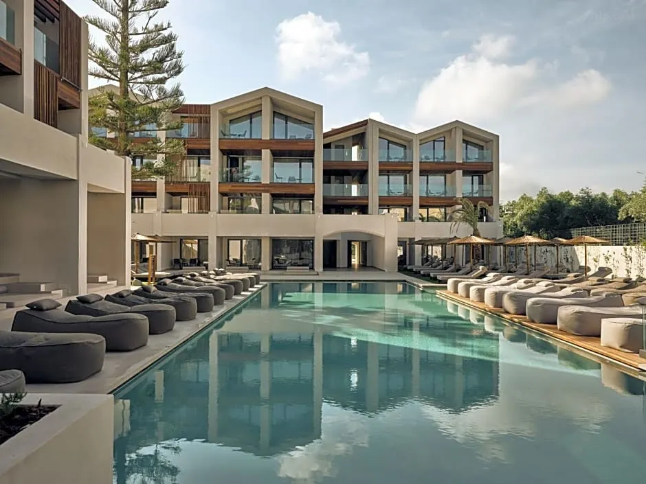 Elegant white architecture of Contessina Hotel in Zakynthos, Greece, nestled among lush gardens, with a sparkling outdoor pool, shaded loungers, and panoramic views of the Ionian Sea under a sunlit sky