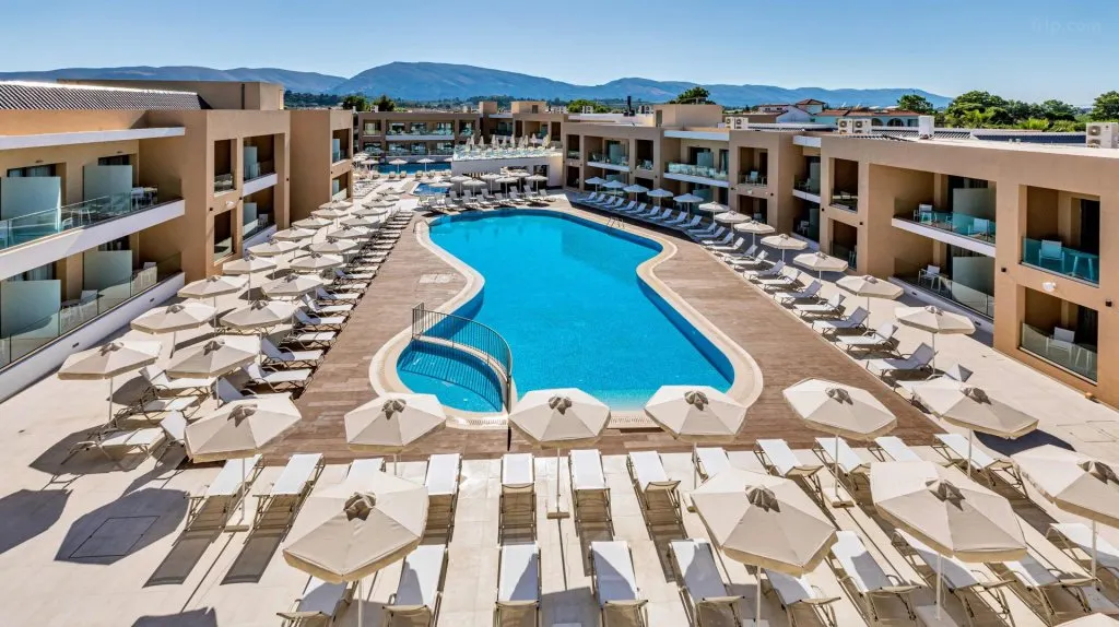 Modern luxury suites at White Olive Elite in Laganas, Greece, with private plunge pools, terraced Mediterranean gardens, and panoramic views of the Ionian Sea’s turquoise waters under a sunlit sky.
