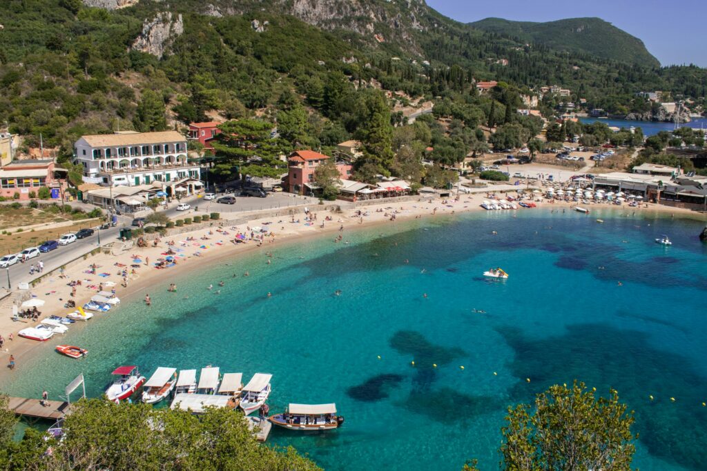 Crystal-clear waters of Paleokastritsa Beach with luxury yachts in the background.