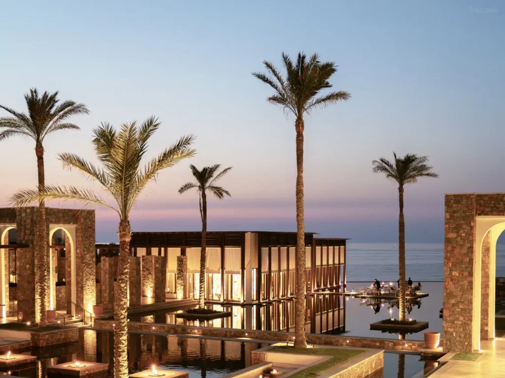 Sunset-lit infinity pool at Crete’s Amirandes Grecotel Resort, flanked by olive groves and a private stretch of Aegean coastline