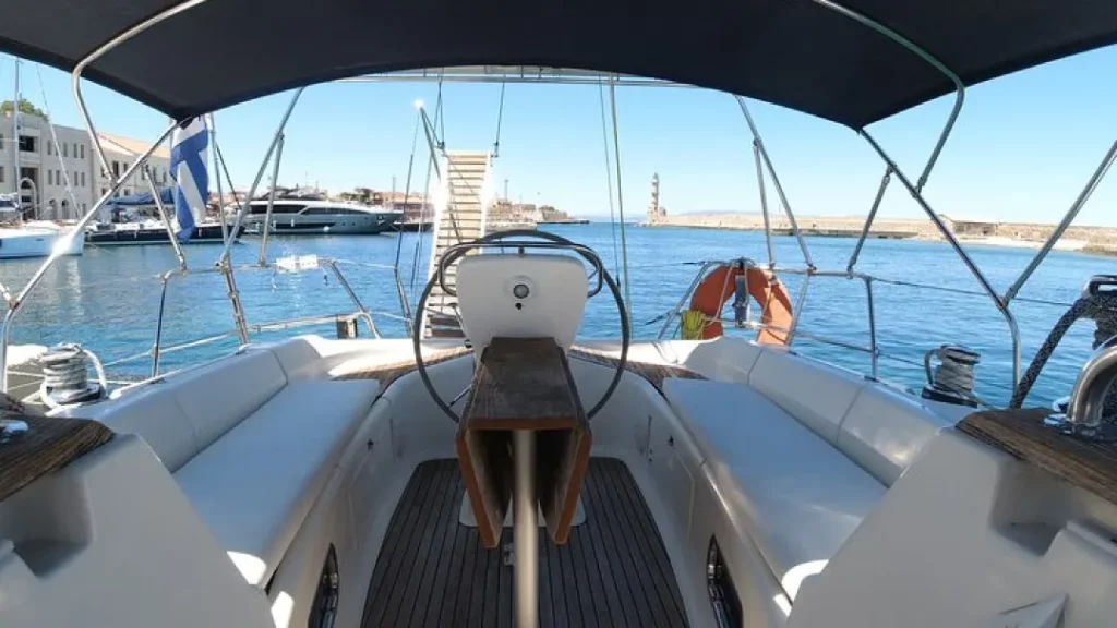 Private sailing yacht glides through Crete’s Chania coastline, guests savoring champagne and gourmet mezze under a golden Mediterranean sunset